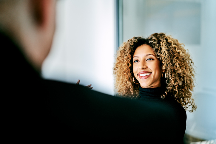 Confident businesswoman in creative office. Smiling female business professional is at workplace. She is having frizzy hair.