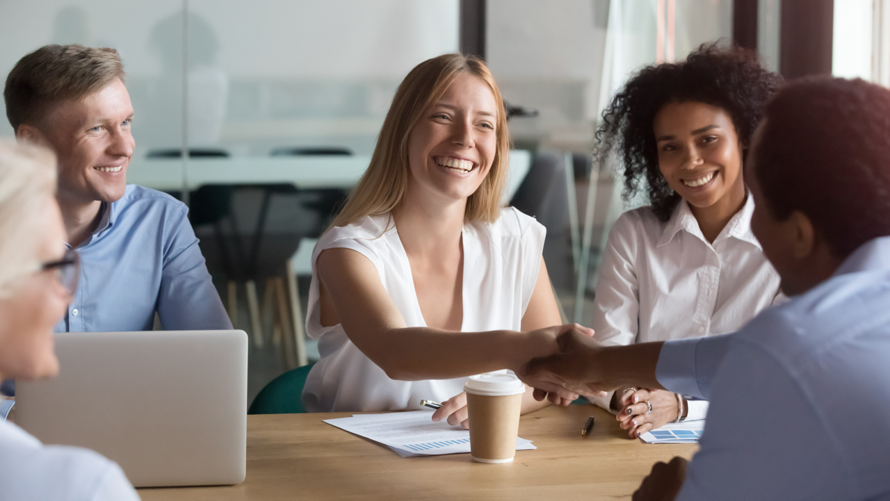 Happy company representative handshaking corporate client at group meeting, cheerful caucasian female manager and african american new business partner shaking hands at negotiations showing respect