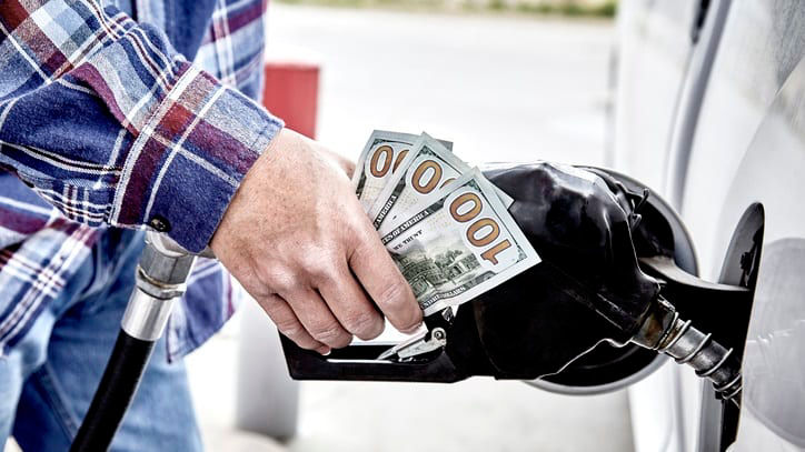 A man is putting money into a gas pump.