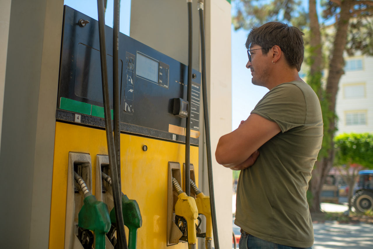 man at gas pump watching prices