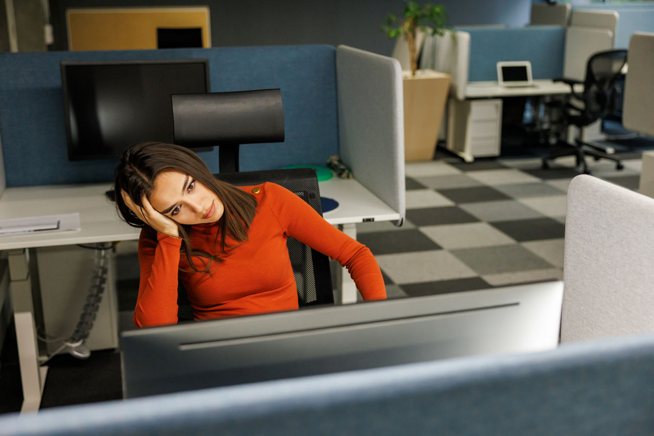 Young woman feeling stressed and having problems while working in modern office at late afternoon