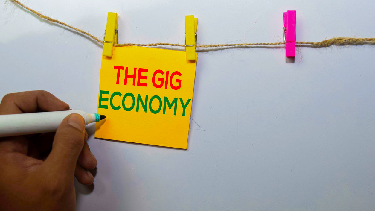 A person writing the word the gig economy on a piece of paper.