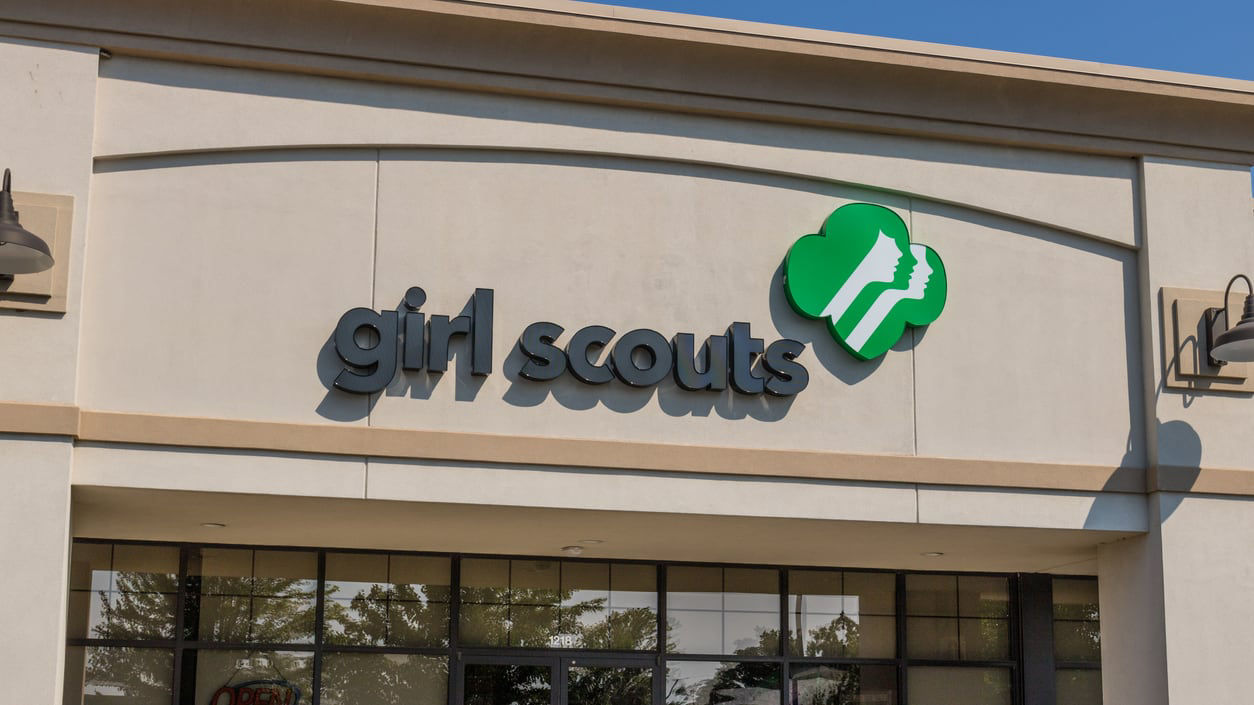 A girl scouts store with a sign in front of it.