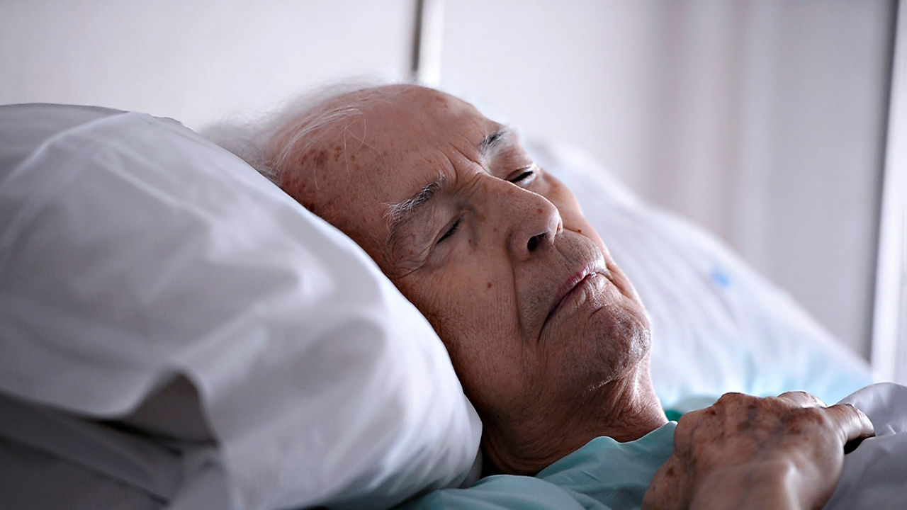 An elderly man is laying in a hospital bed.