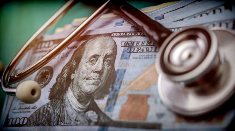 A stethoscope sits on top of a stack of money.