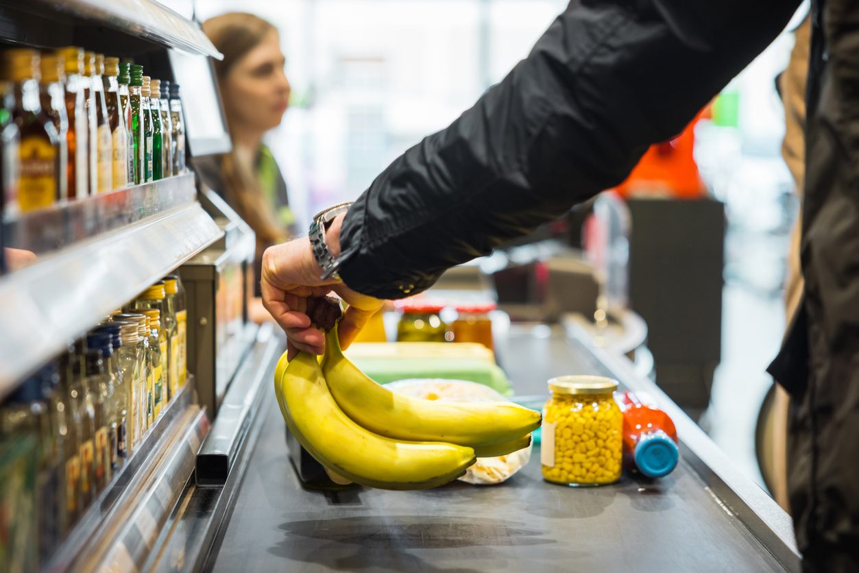 person checking out bananas and other groceries at store