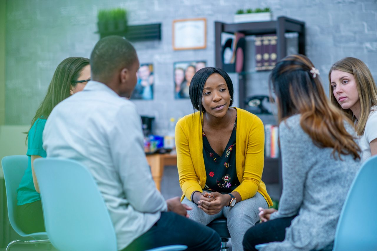 A diverse group of adults sit in a circle