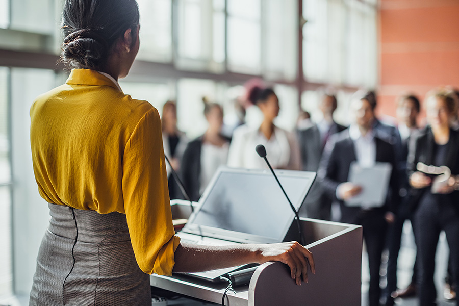 Woman at a podium speaking to a group of people
