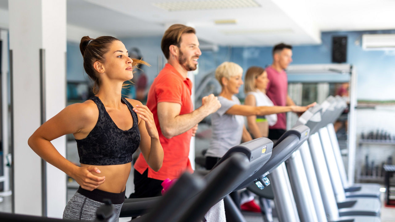 A group of people running on treadmills in a gym.