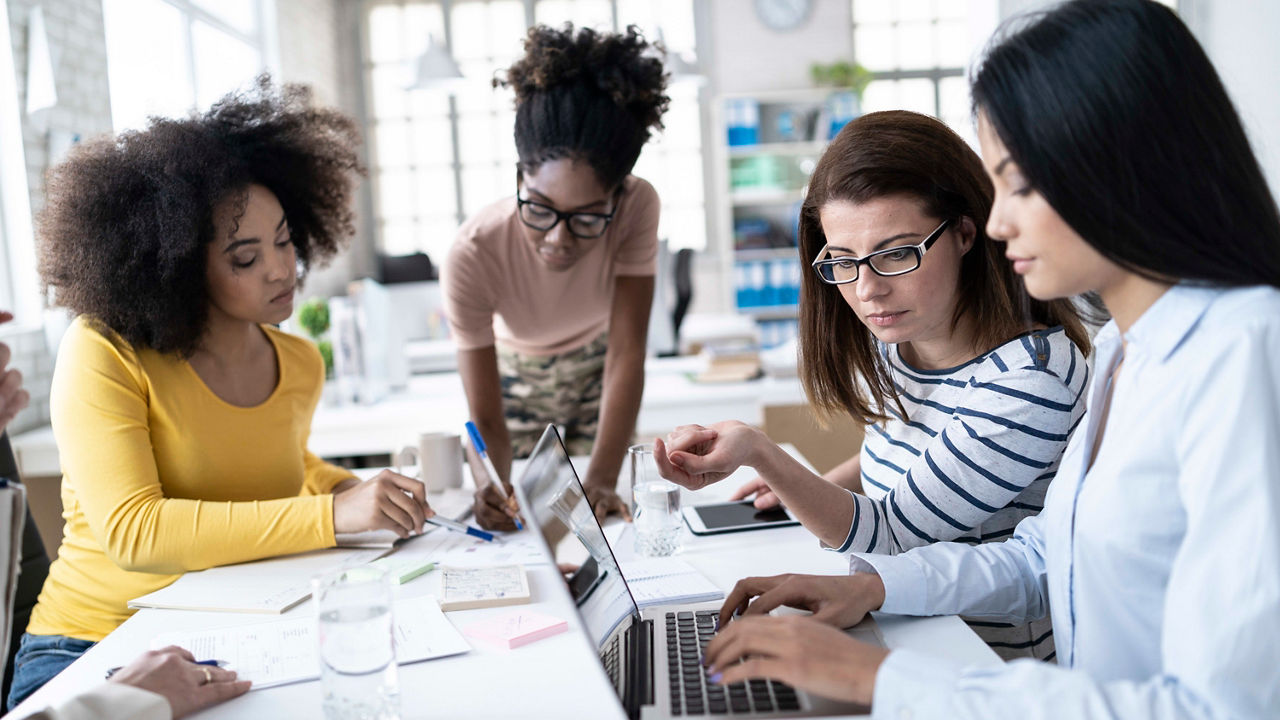 A group of women working on laptops in an office.
