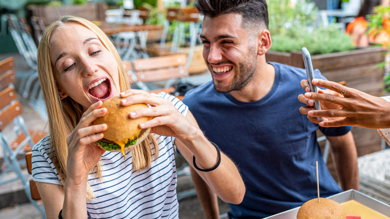 A group of people eating burgers in a restaurant.