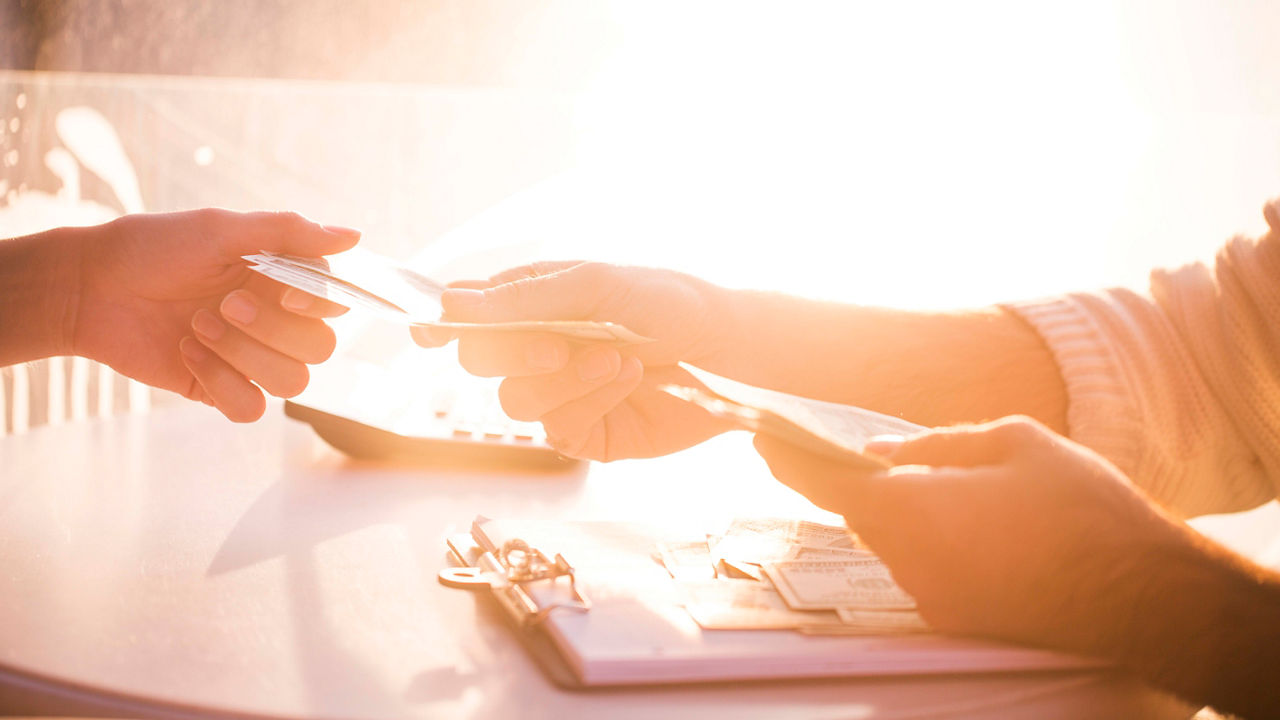 A man is handing a credit card to another person at a table.