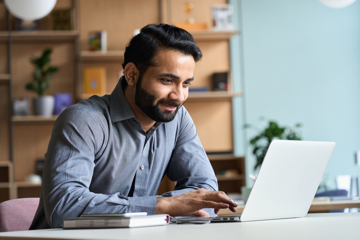 Smiling business man working on laptop in office. 