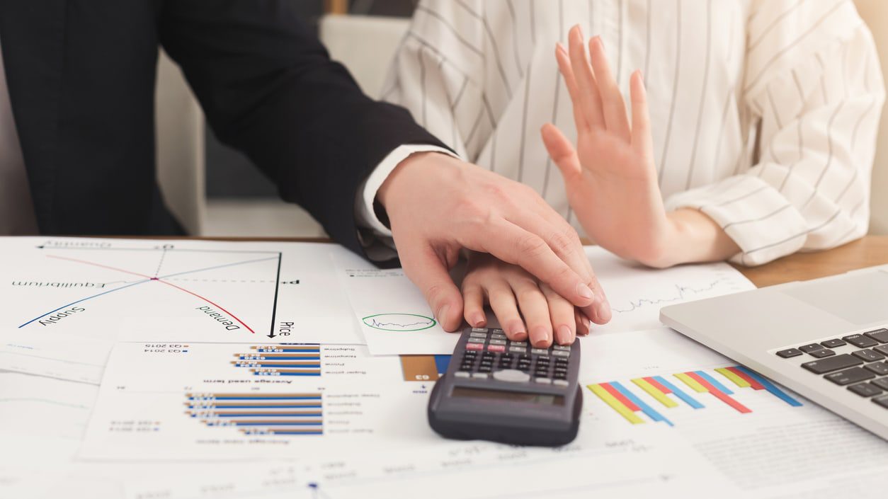 A businessman and woman holding a calculator at a desk.