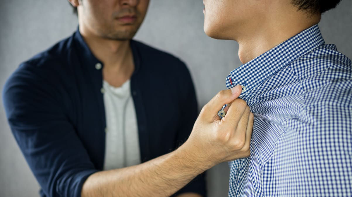 A man putting a tie on another man.