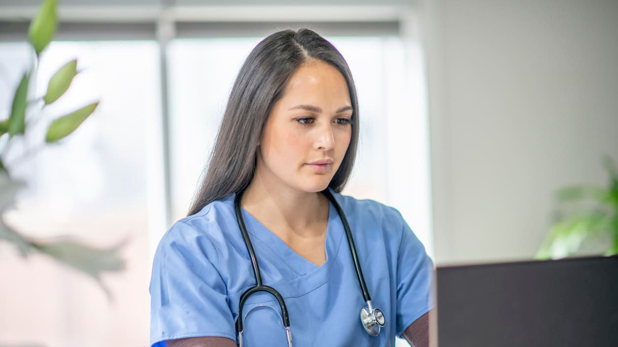 A female nurse working on a laptop computer.