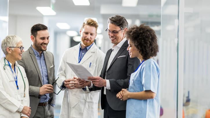A group of doctors and nurses talking in a hospital hallway.