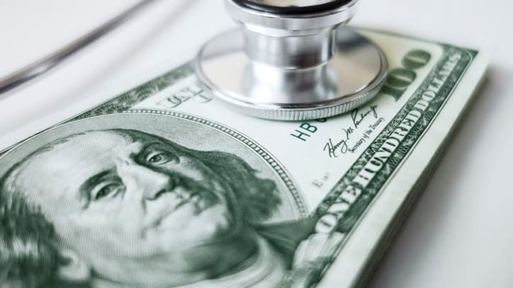 A stethoscope sits on top of a dollar bill.