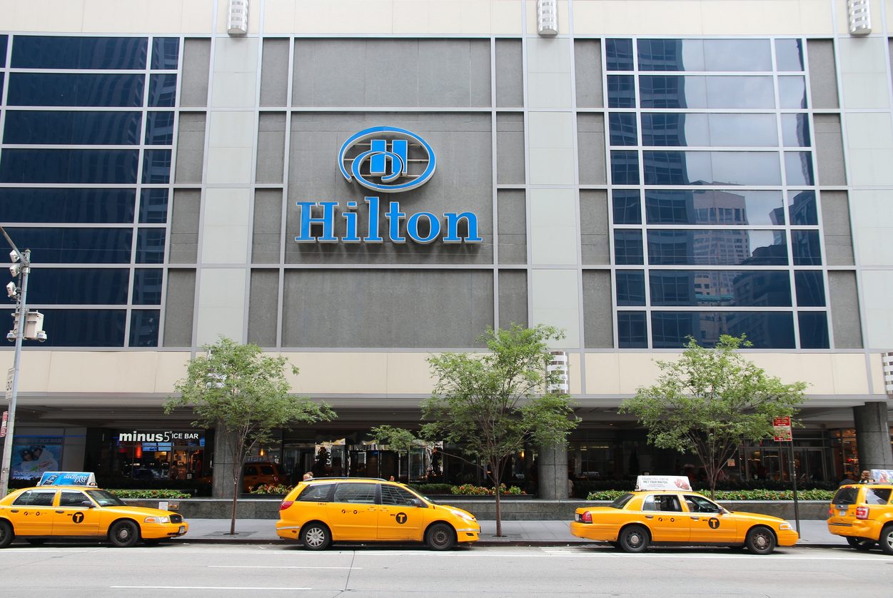 Outside photo of Hilton hotel with yellow cabs in front of the building