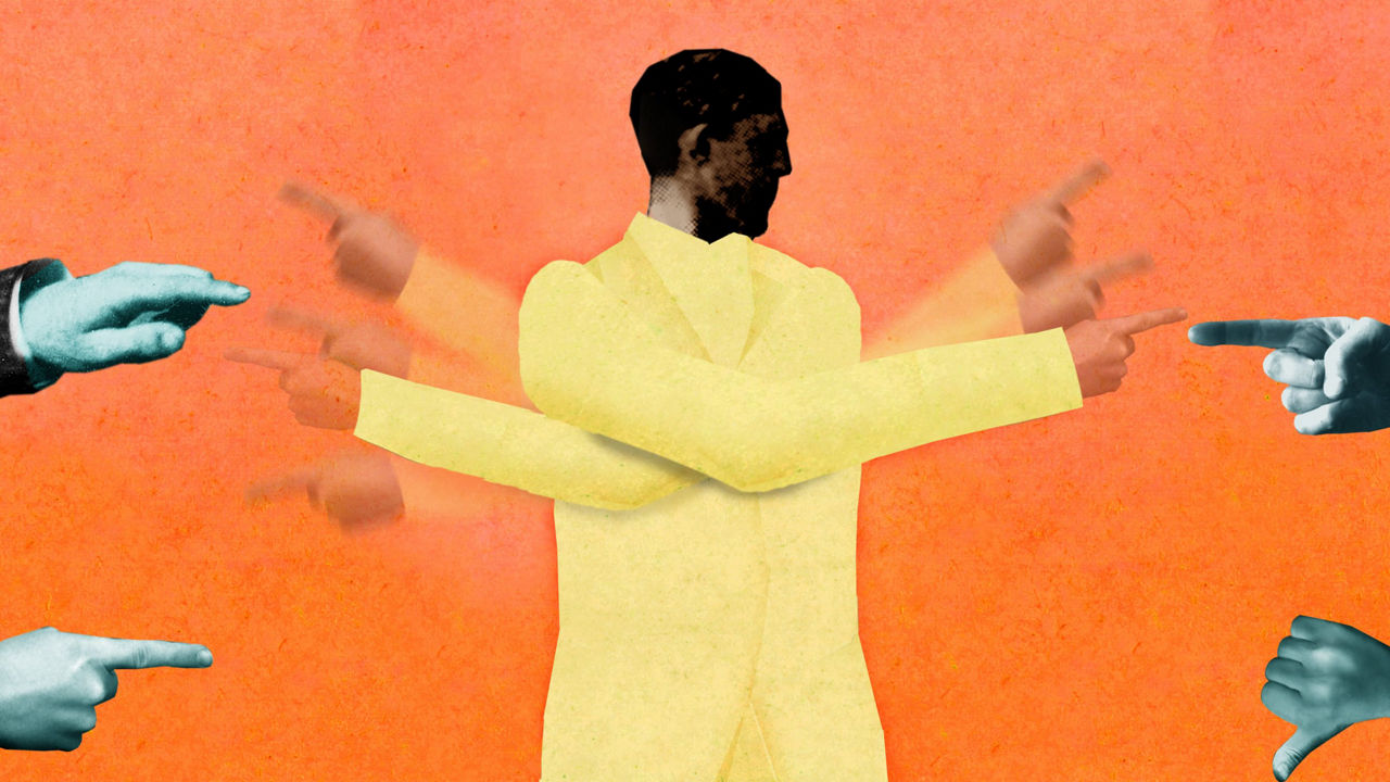 A man in a yellow suit is pointing his fingers at a group of people.