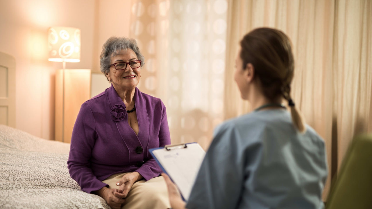 A nurse talking to an elderly woman in a hospital room.