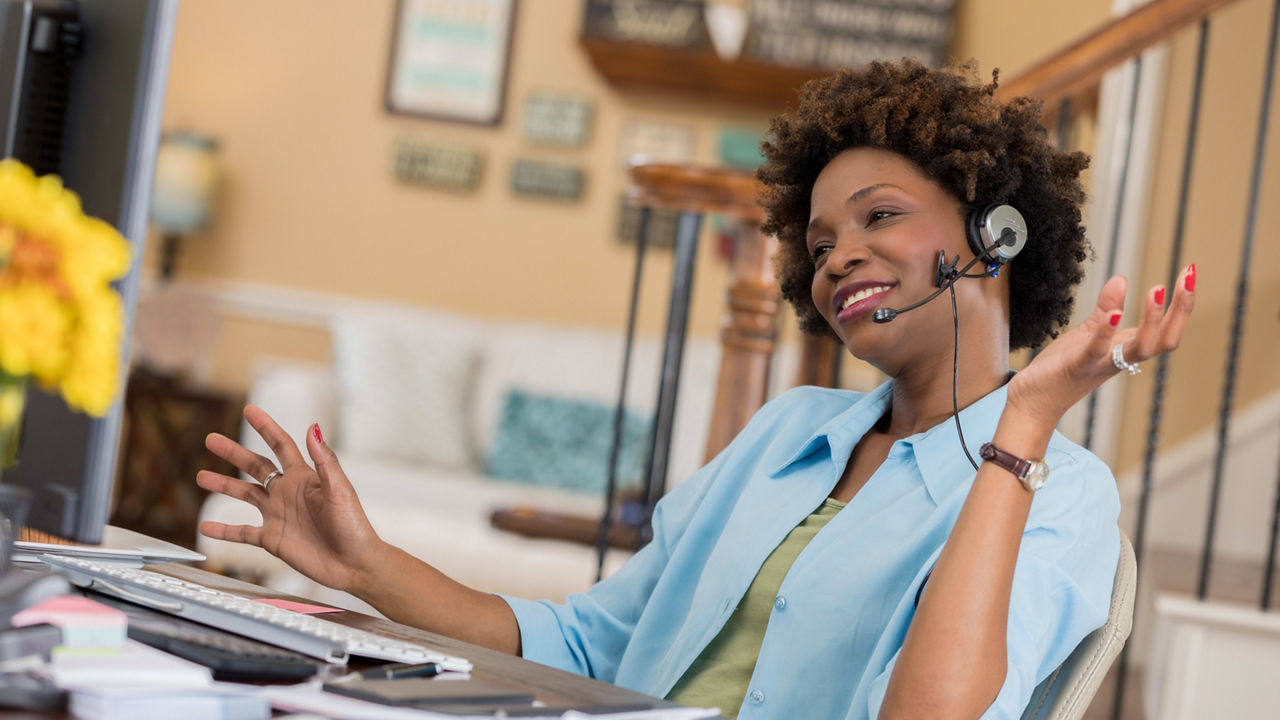 A woman wearing a headset is working at home.