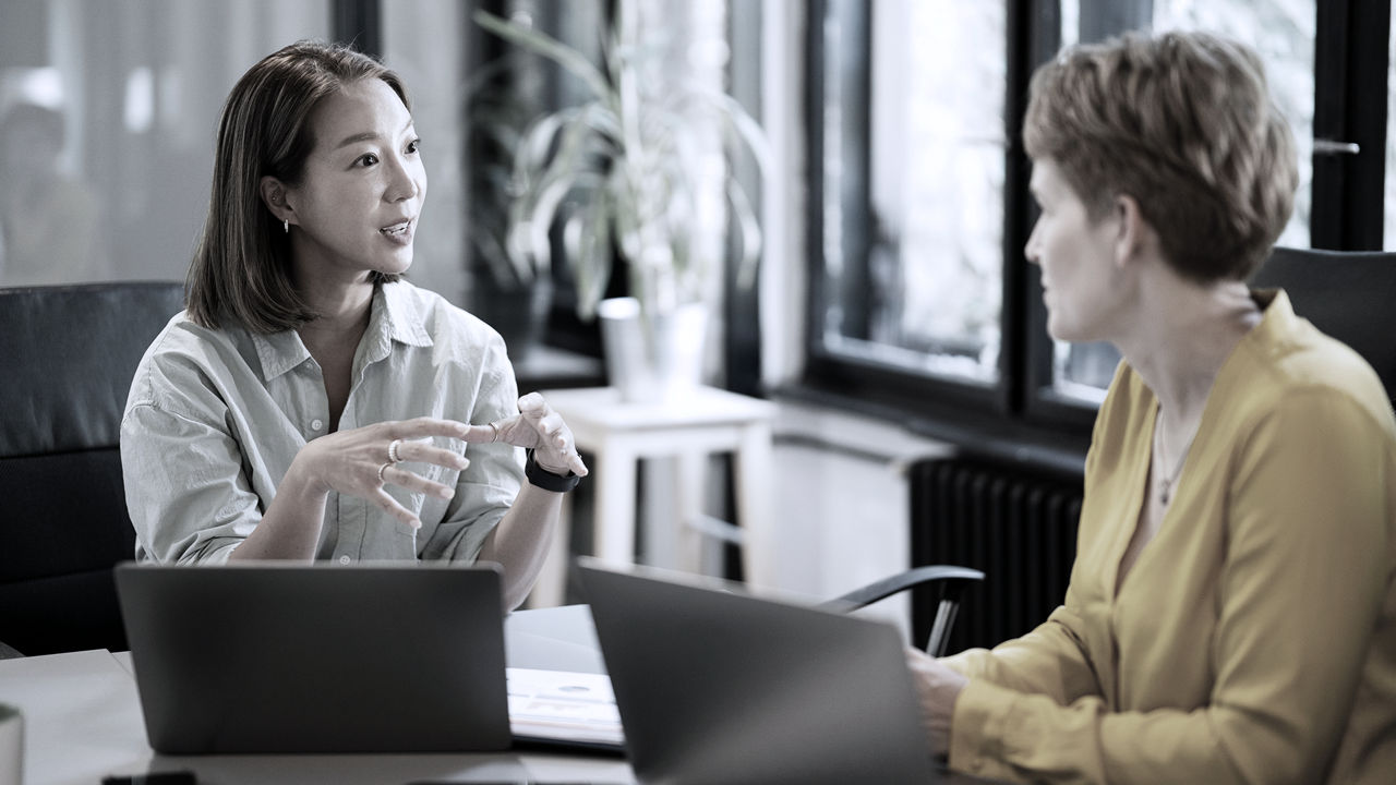 Leader talking to a team member, both sitting at a table