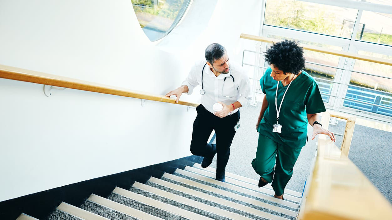 Two nurses walking up the stairs in a hospital.