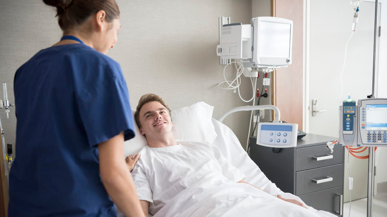 A nurse talking to a patient in a hospital bed.