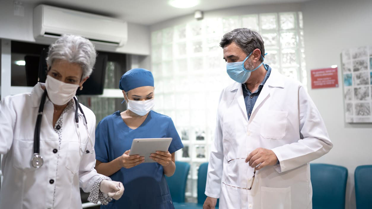A group of doctors and nurses standing in a hospital room.