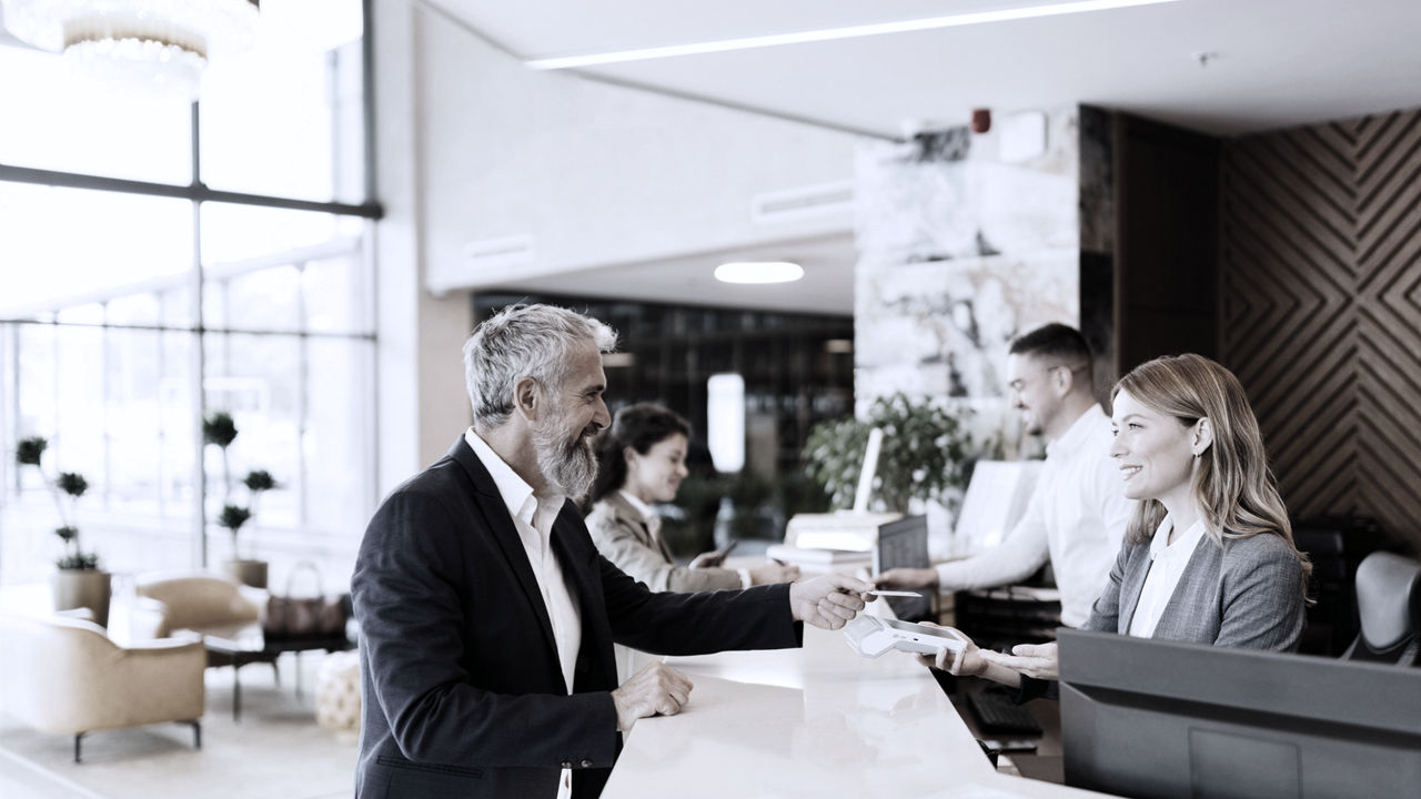 Two people talking to front desk staff in hotel lobby