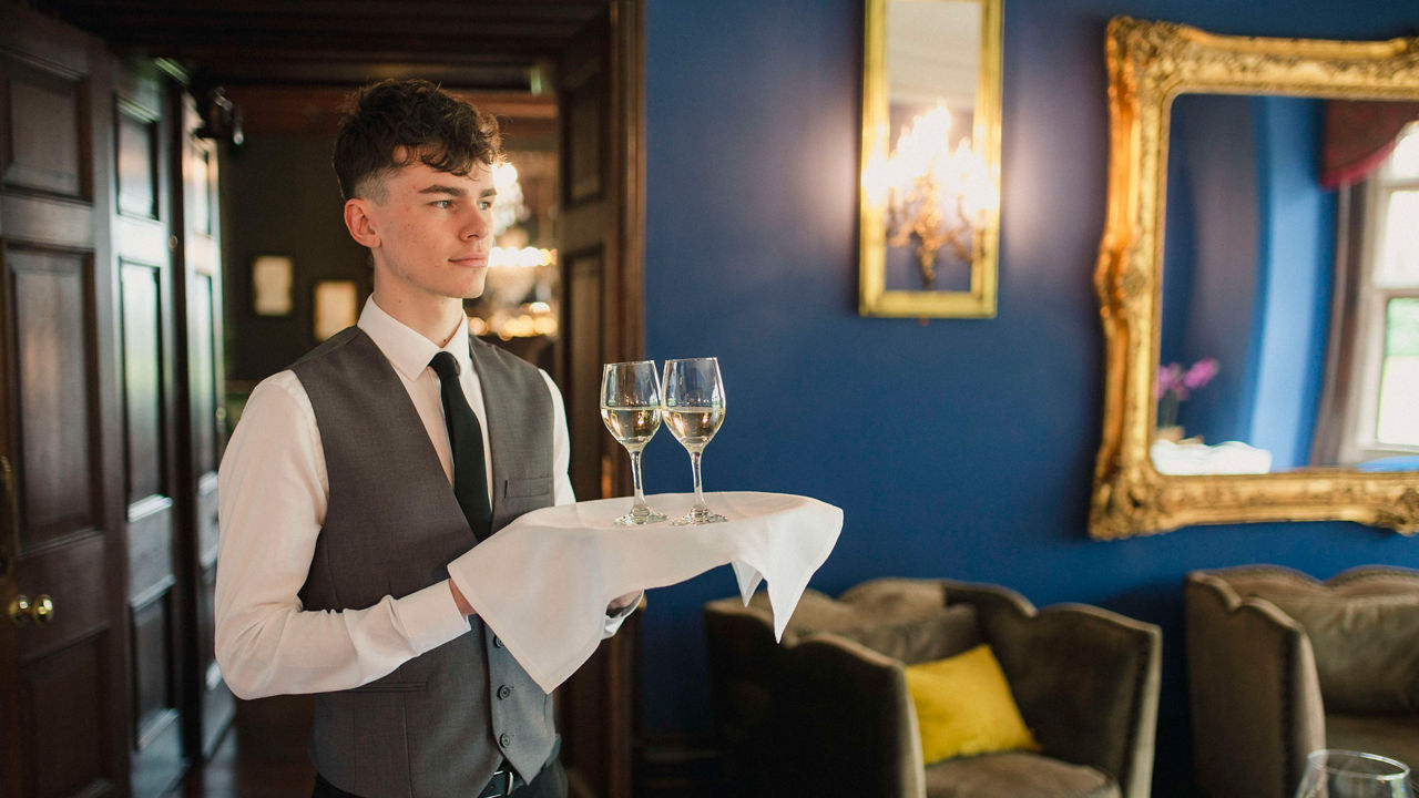 A waiter holding a tray of wine glasses.