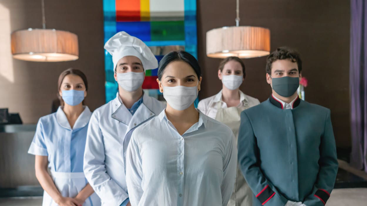 A group of people wearing surgical masks in a hotel.