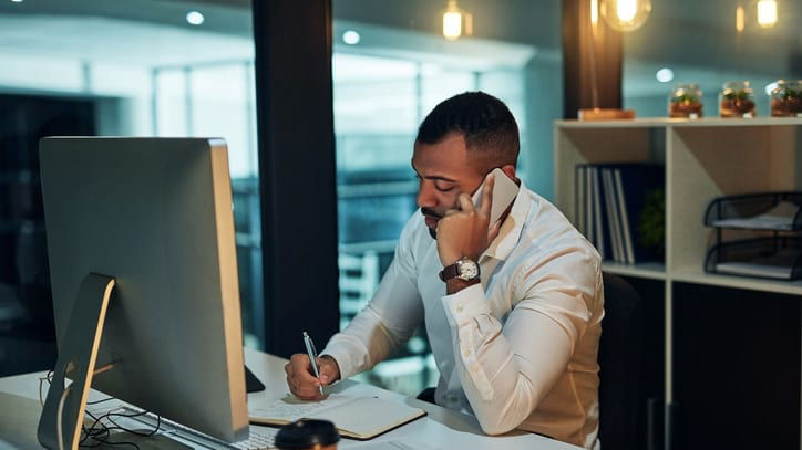 A man sitting at a desk and talking on the phone.