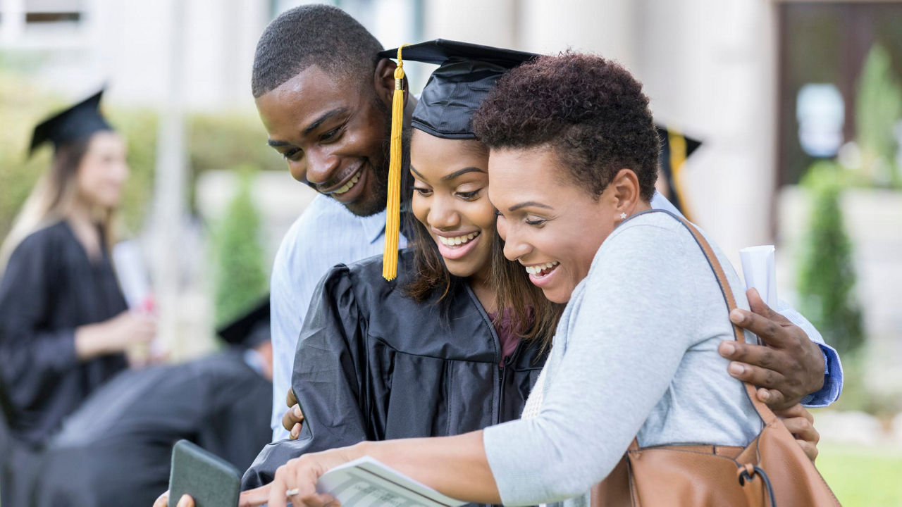 A group of graduates looking at a tablet.
