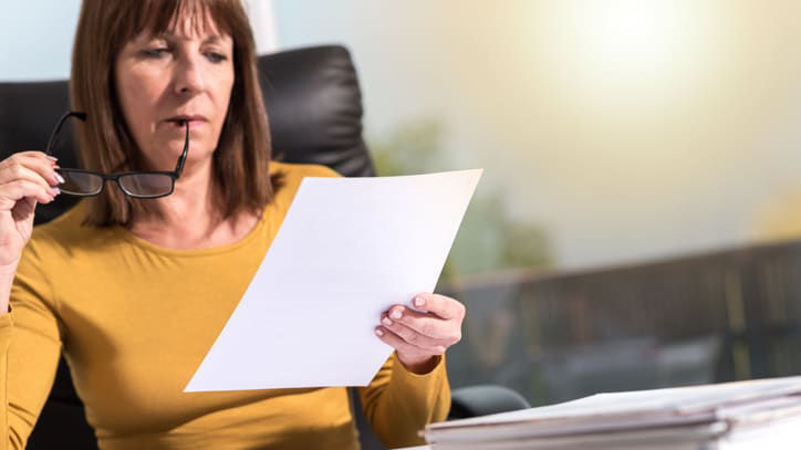 A woman looking at a piece of paper at her desk.