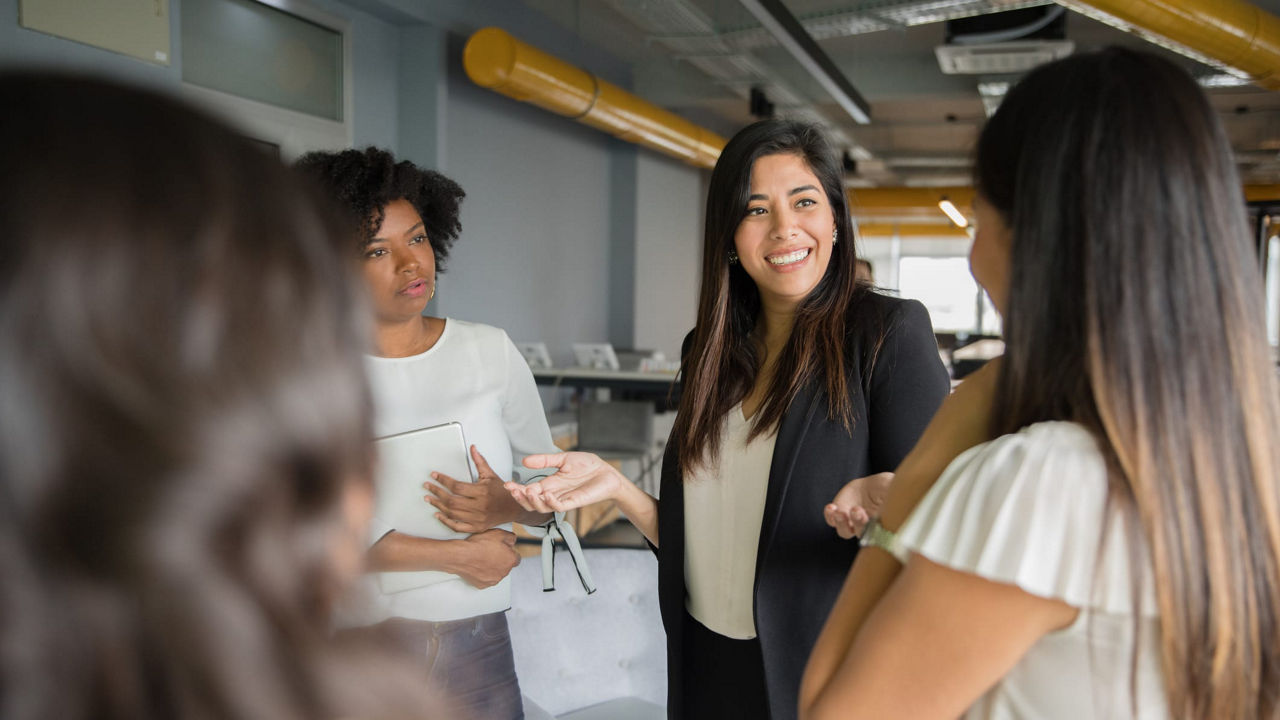 A group of business women talking to each other in an office.