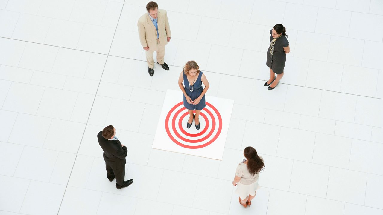 A group of business people standing around a target.