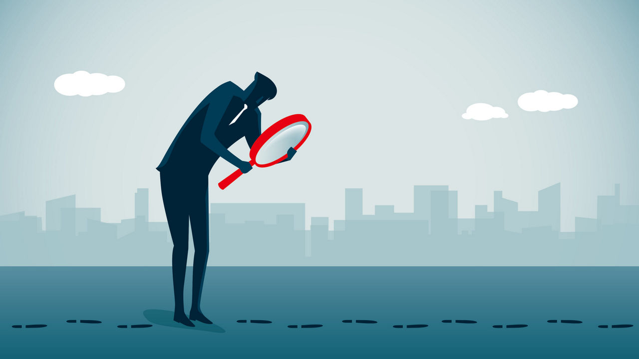 A businessman looking through a magnifying glass.