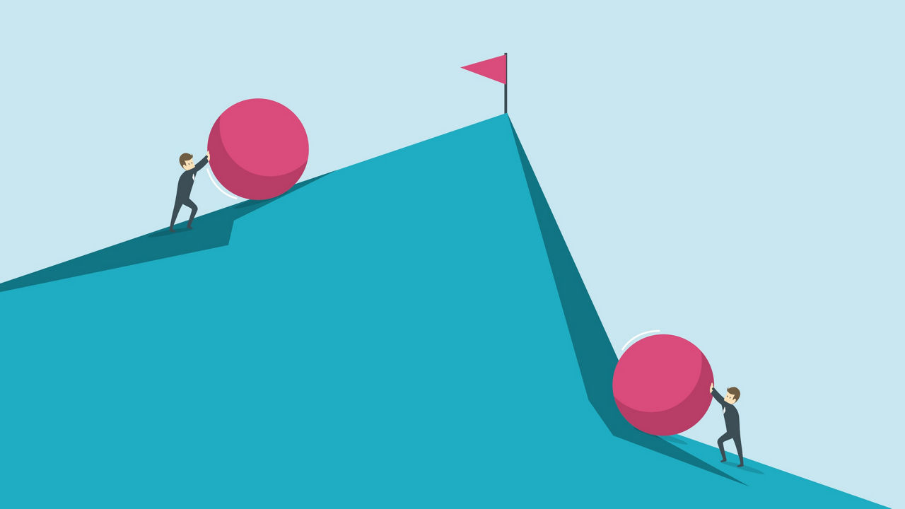 Two businessmen pushing a pink ball up a mountain.