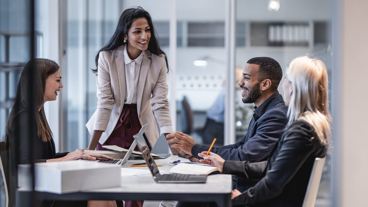 A group of business people sitting around a table in an office.