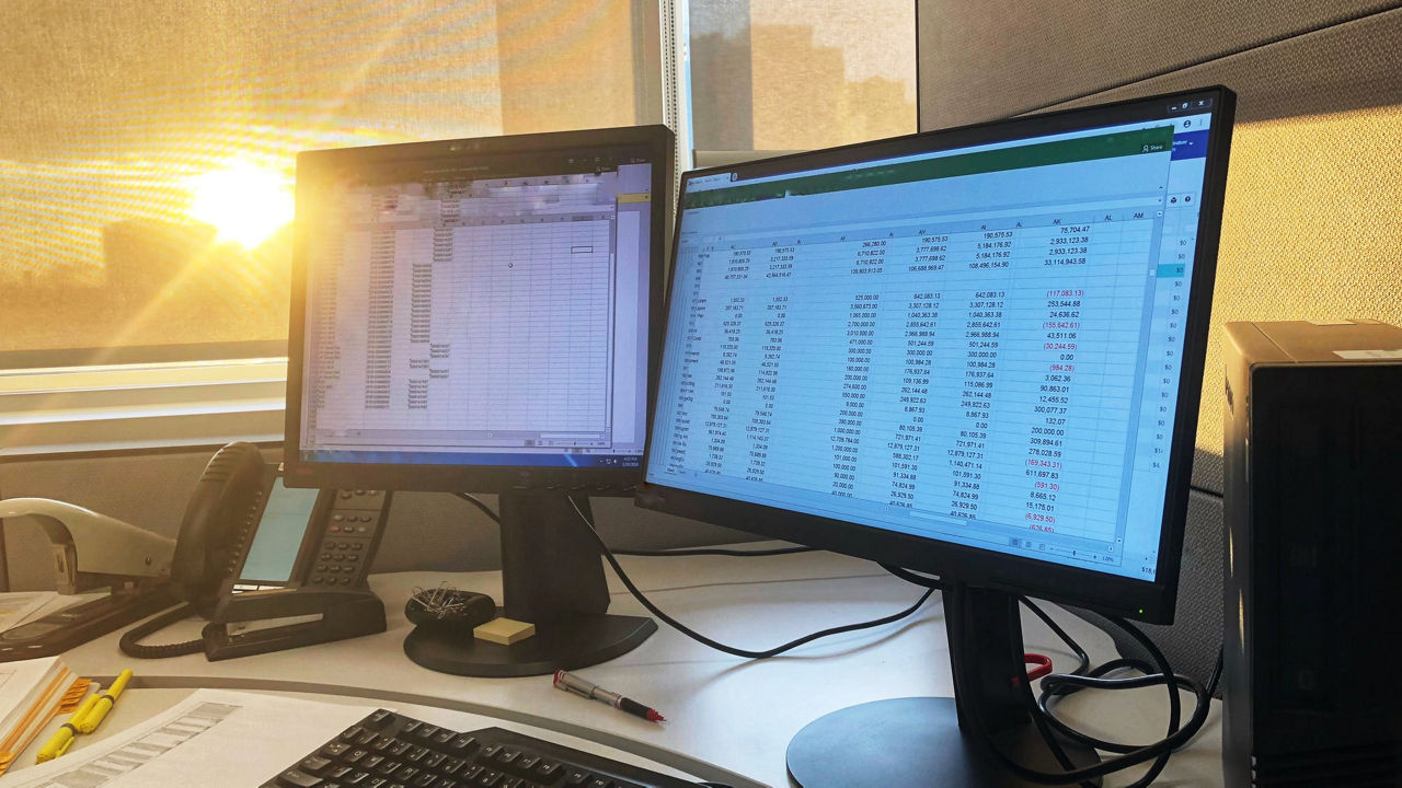 A desk with two monitors and a keyboard.