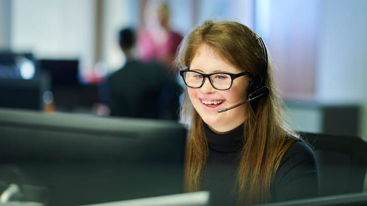 A woman wearing glasses and a headset in a call center.