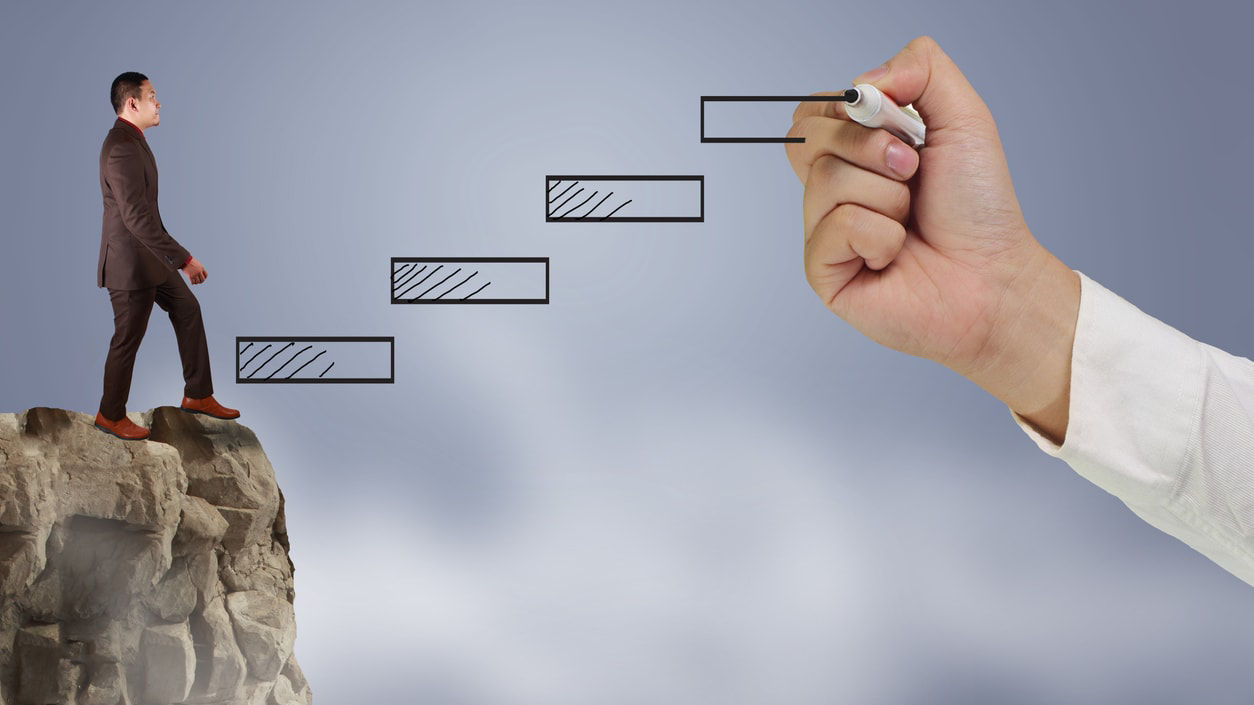 A businessman is standing on top of a cliff.