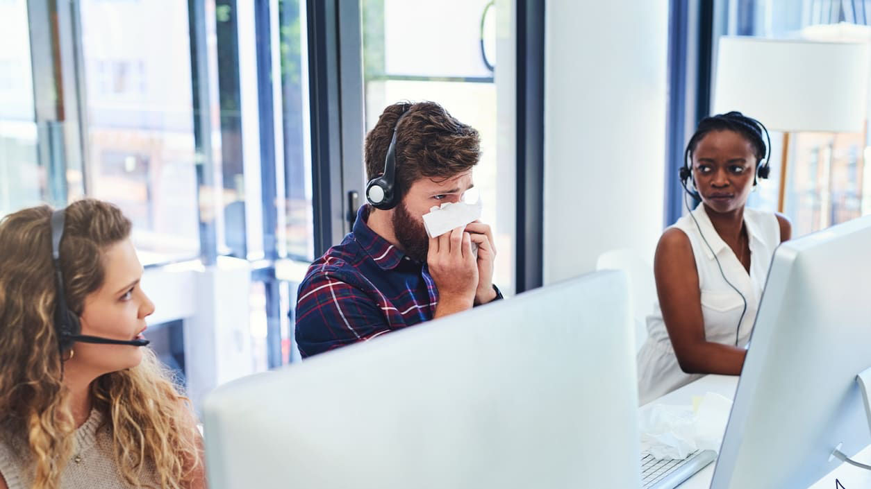 A group of people in a call center wearing headsets.