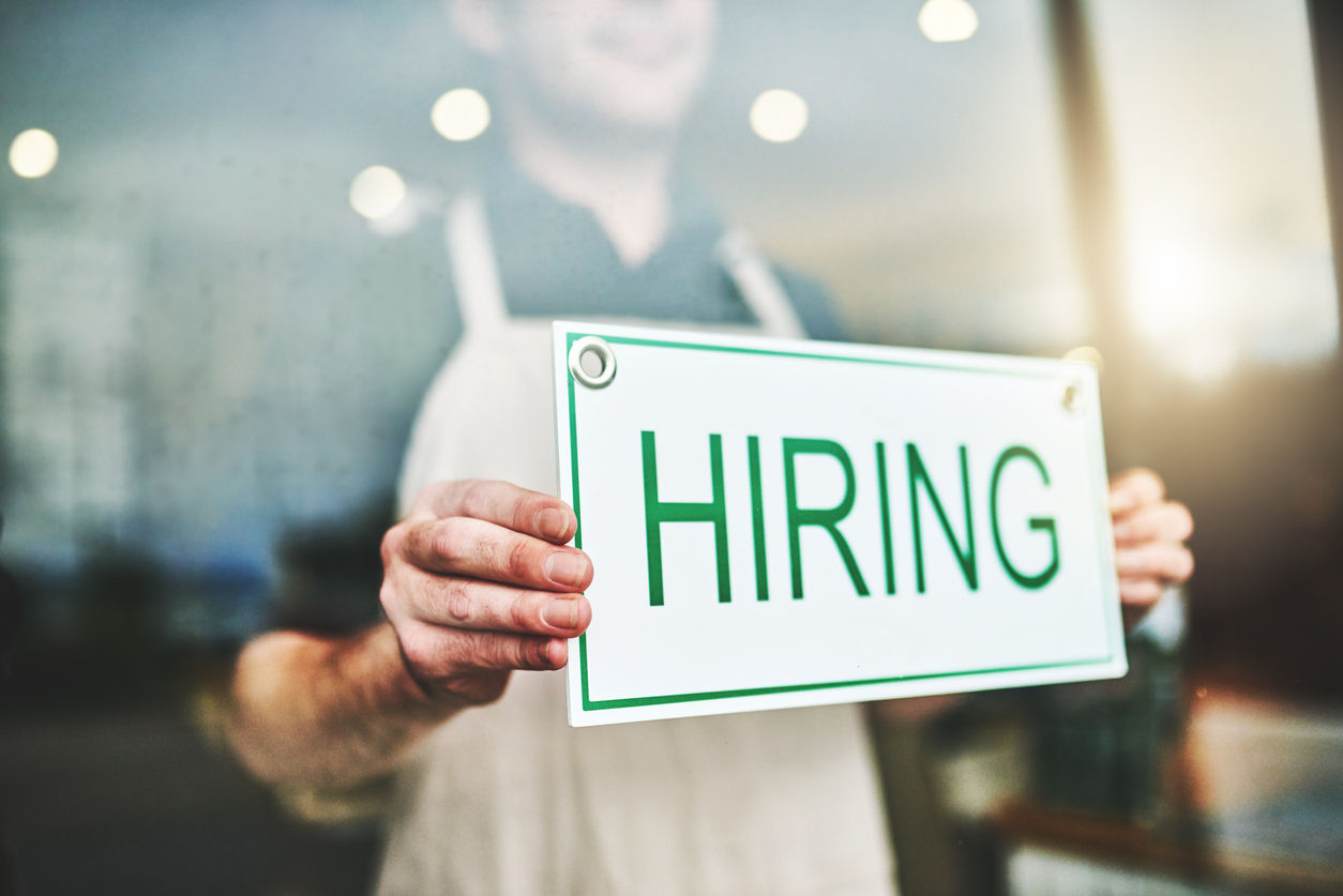 Person putting hiring sign in window