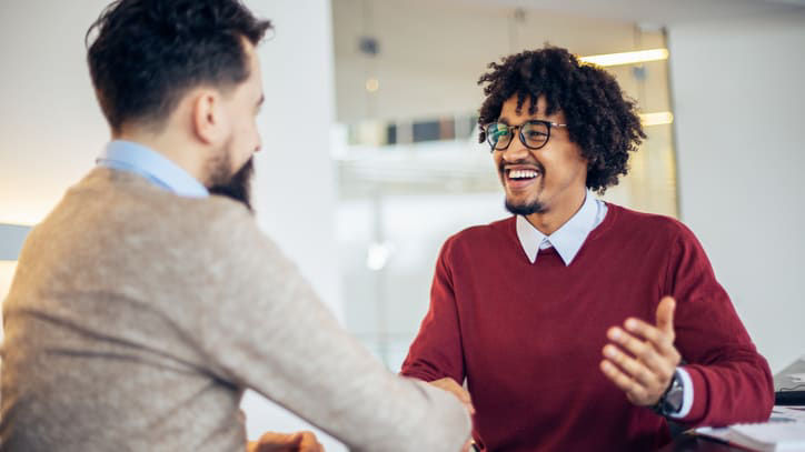 Two men shaking hands in an office.