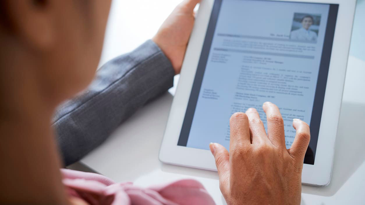 A woman is using a tablet to look at a resume.