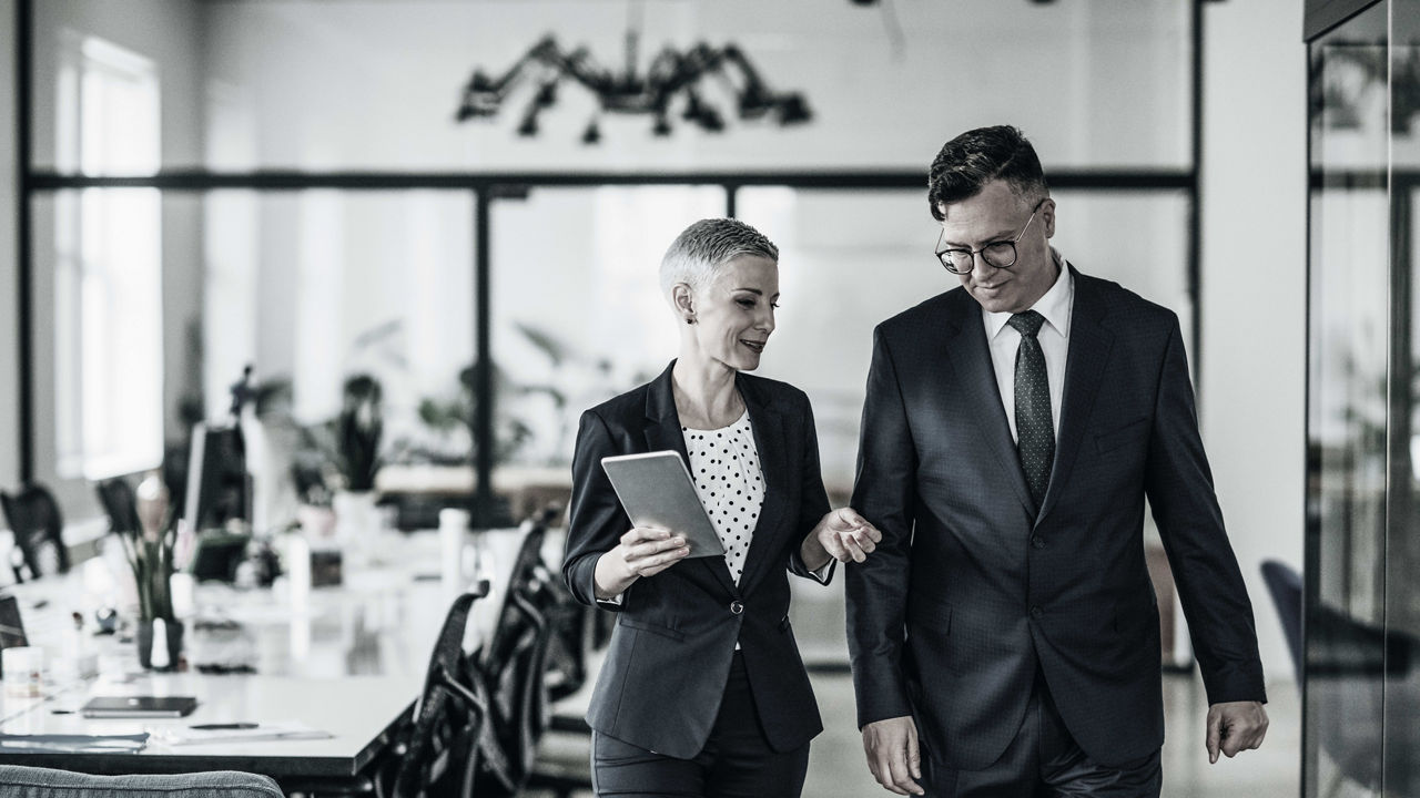 Two business people walking in an office.