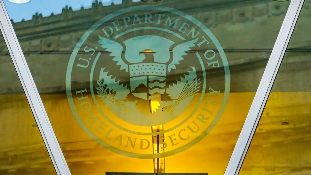 The u s department of homeland security logo is reflected in the glass of a building.